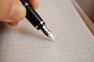 Eine Hand hält einen Füller, der auf einem weißen, kariertem Blatt liegt. © Landkreis Rotenburg (Wümme)
